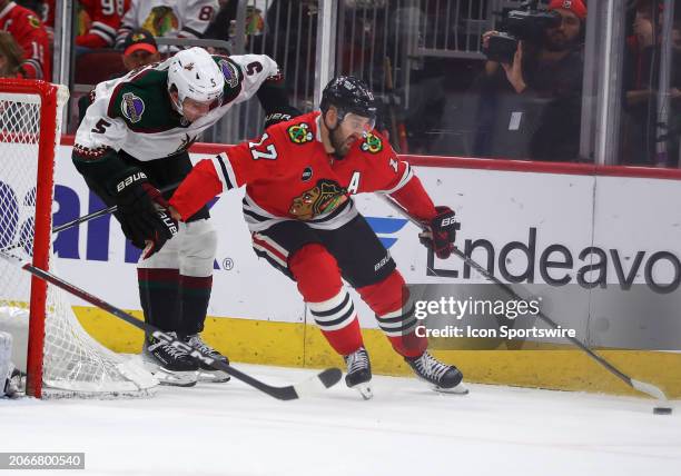 Nick Foligno of the Chicago Blackhawks controls the puck against Michael Kesselring of the Arizona Coyotes during the third period at the United...