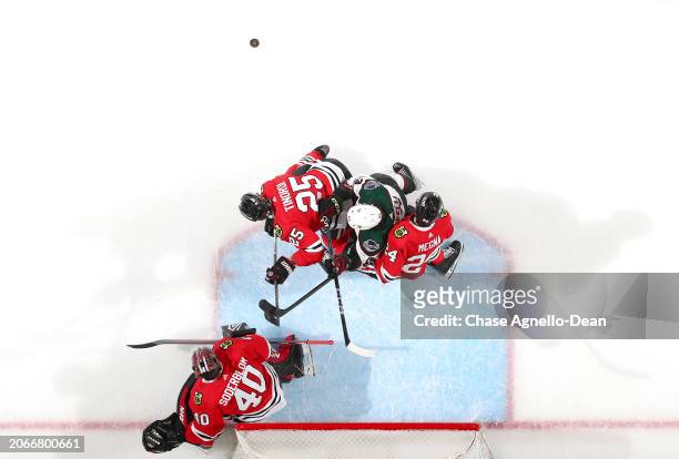 Matias Maccelli of the Arizona Coyotes stands in position in between Jarred Tinordi and Jaycob Megna of the Chicago Blackhawks ini the second period...