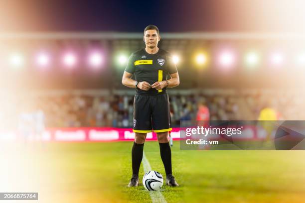 confident male football referee standing on the field at night - referee uniform stock pictures, royalty-free photos & images