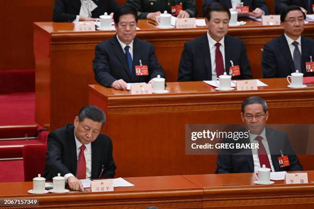 China's President Xi Jinping votes as China's Premier Li Qiang looks on during the closing session of the 14th National People's Congress at the...