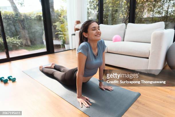 beautiful young woman doing yoga or exercise in living room at home, healthy lifestyle or sports training concept. - flatten the curve imagens e fotografias de stock