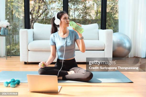 beautiful young woman drinking water while doing exercise or yoga in living room at home. healthy lifestyle or sports training concept. - flatten the curve fotografías e imágenes de stock