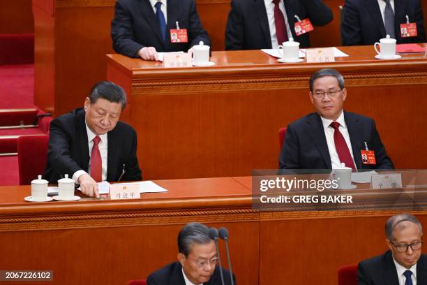 China's President Xi Jinping votes as China's Premier Li Qiang looks on during the closing session of the 14th National People's Congress at the...
