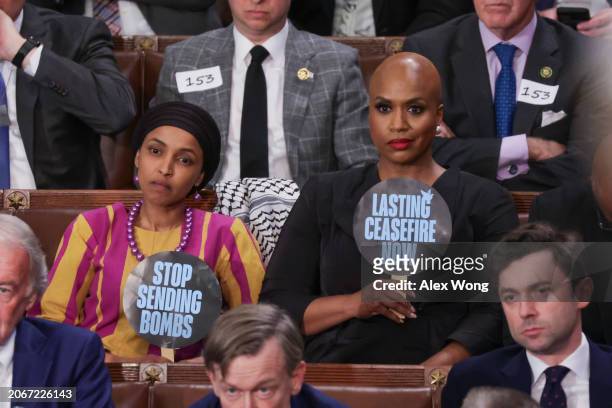 Rep. Ilhan Omar and Rep. Ayanna Pressley hold up signs as President Joe Biden delivers the State of the Union address during a joint meeting of...