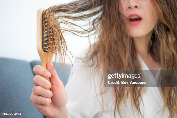 cropped shot view of asian woman having hair stuck problem when she trying to brushing her hair with a comb. - tangled hair stock pictures, royalty-free photos & images