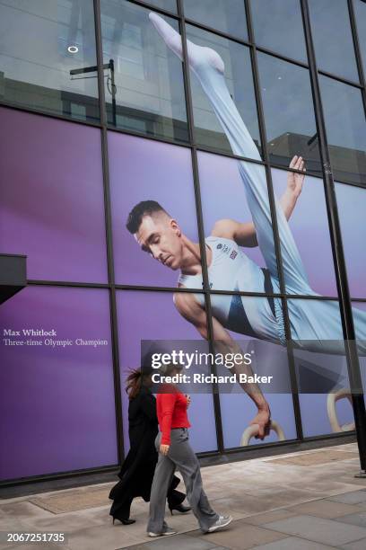 With months before the 2024 Paris Olympics, members of the public pass beneath a huge image of Team GB gymnast and previous Olympic gold medalist,...