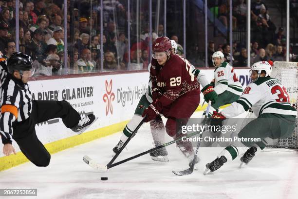 Barrett Hayton of the Arizona Coyotes skates with the puck under pressure from Ryan Hartman of the Minnesota Wild during the second period of the NHL...