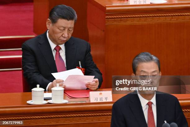 China's President Xi Jinping looks through documents as Chairman of the Standing Committee of the National People's Congress Zhao Leji speaks at the...