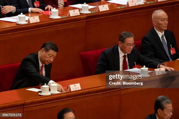 Xi Jinping, China's president, left, and Li Qiang, China's premier, second right, cast ballots during the closing of the Second Session of the 14th...