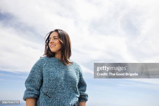 portrait of young woman standing against sky on sunny day - zufriedenheit stock-fotos und bilder