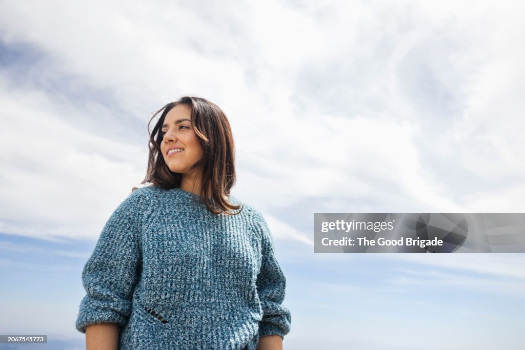Portrait of young woman standing against sky on sunny day