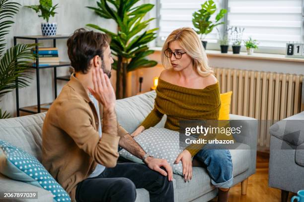 junges paar streitet sich zu hause auf dem sofa - menschliche beziehung stock-fotos und bilder