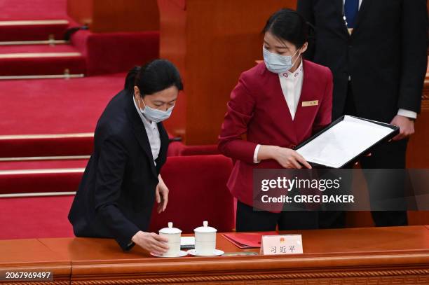 An attendant places one of Chinese President Xi Jinping's two teacups on his desk before the closing session of the National People's Congress at the...