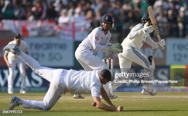 Jasprit Bumrah of India hits the ball past Joe Root as Ben Foakes looks on during day two of the 5th Test Match between India and England at Himachal...