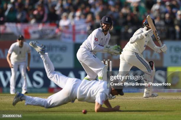 Jasprit Bumrah of India hits the ball past Joe Root as Ben Foakes looks on during day two of the 5th Test Match between India and England at Himachal...