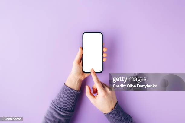 female hands holding smart phone with blank isolated white screen and space for text on trendy lavender color - main humaine photos et images de collection
