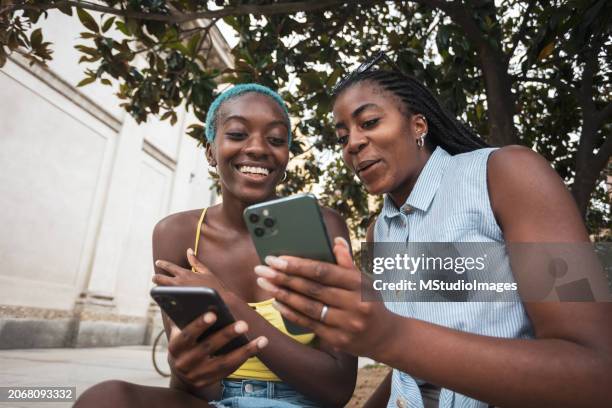 two african friends using mobile phone - brand name mobile payment stock-fotos und bilder