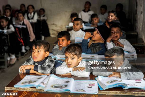 Students attend class at the mixed-gender al-Tafawuq elementary school, which rents mud brick buildings with thatched roofs on a farm to be used as...