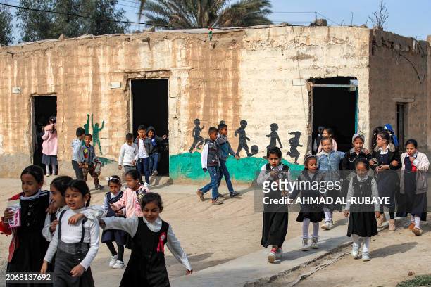 Students walk outside one of the mud brick buildings with thatched roofs on a farm, used as makeshift classrooms by the mixed-gender al-Tafawuq...