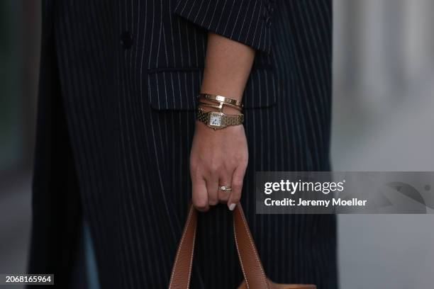 Aylin Koenig seen wearing By Aylin Koenig black pinstriped oversized long coat, Hermès Picotin brown leather bag, Cartier Panthère yellow gold watch,...