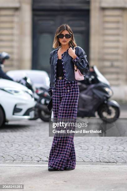 Guest wears sunglasses, a black leather jacket with tweed borders, a black low-neck top, a pastel pale pink bag, blue and purple checkered / checked...