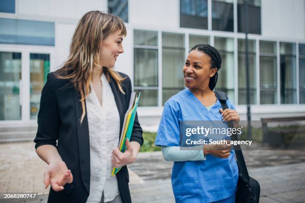 nurse coming to new work and recruiter is welcoming her in front of the hospital - recruiter stockfoto's en -beelden