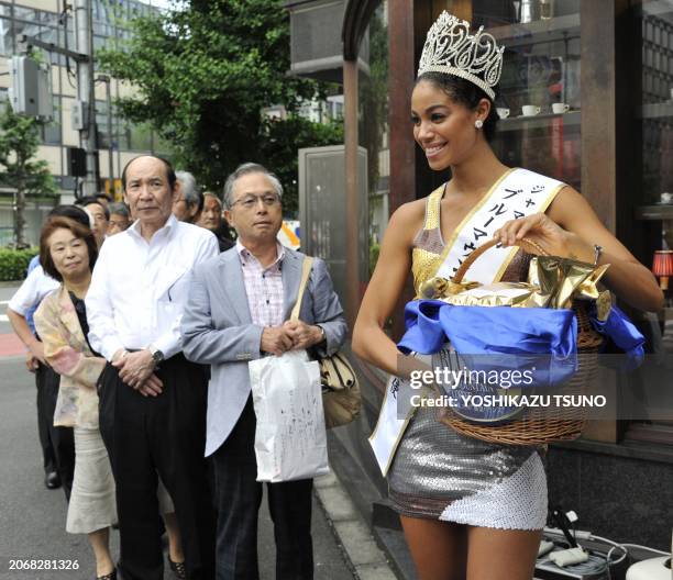 Miss Jamaica Yundi Phillips the first runner-up of the Miss Universe 2010 beauty pageant hands out a package of Jamaica's Blue Mountain coffee beans...