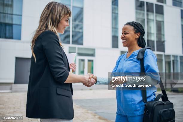 l'infermiera che arriva al nuovo lavoro e il reclutatore la accoglie davanti all'ospedale - recruiter foto e immagini stock