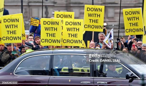 Demonstrator of the anti-monarchy group Republic hold placards reading "Down with the crown" as Britain's Queen Camilla arrives to attend an annual...