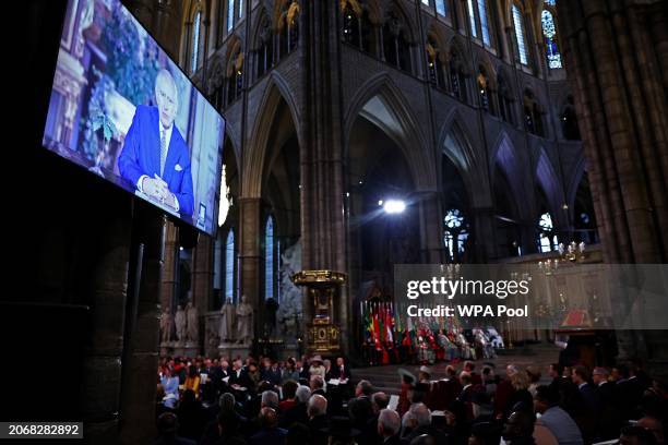 Guests watch a video of Britain's King Charles III delivering a message during the 2024 Commonwealth Day Service at Westminster Abbey on March 11,...