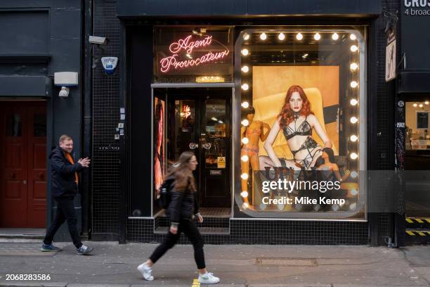 Digital advertising images of female models and mannequins wearing luxury underwear in the shop window of Agent Provocateur in Soho, interacting with...