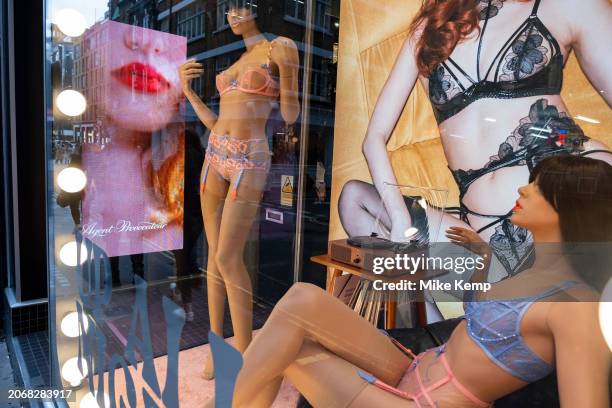 Digital advertising images of female models and mannequins wearing luxury underwear in the shop window of Agent Provocateur in Soho, interacting with...