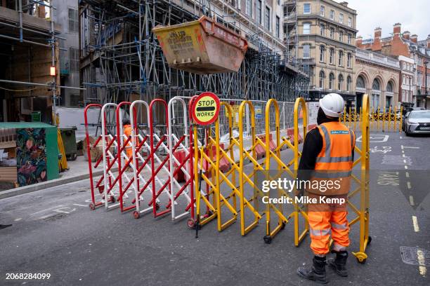 Construction worker attends barriers while he watches a skip being hoisted into the air by crane on a major construction site in Covent Garden on 6th...