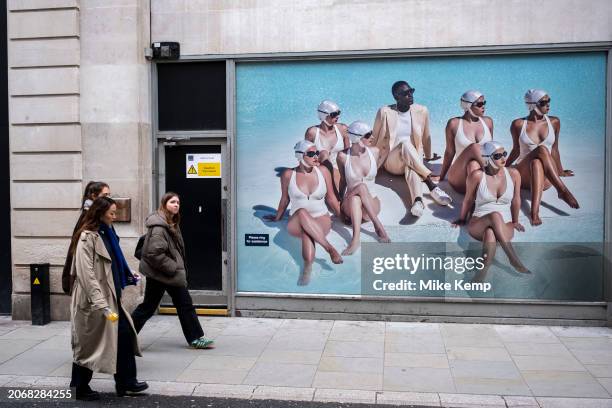 Advertising imagery featuring several women in formation wearing white bathing suits and swimming caps sitting in water with a male wearing a suit...