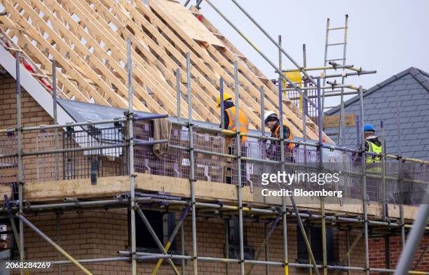Workers lay insulation material on a roof at a Persimmon Plc residential property construction site in Braintree, UK, on Monday, March 11, 2024....