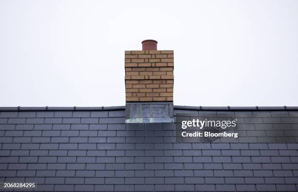 The chimney stack and roof tiles of a new home at a Persimmon Plc residential property construction site in Braintree, UK, on Monday, March 11, 2024....