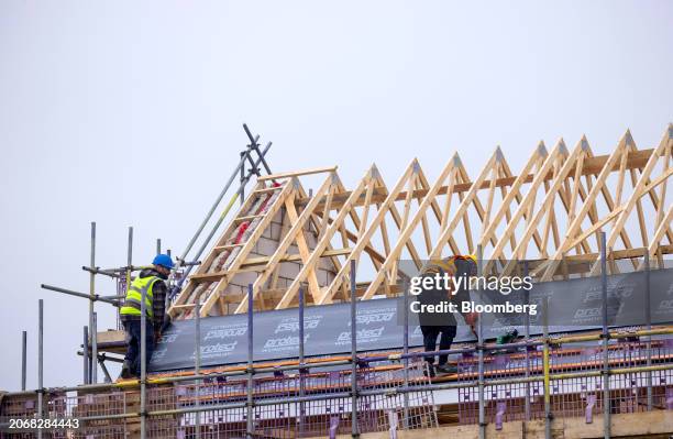 Employees lay roof insulation material on joists at a Persimmon Plc residential property construction site in Braintree, UK, on Monday, March 11,...