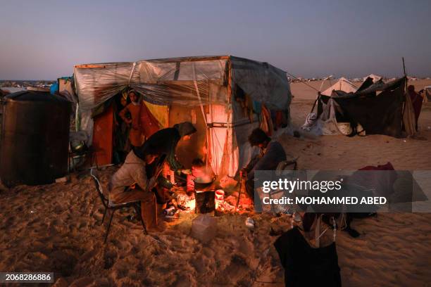 Displaced Palestinians prepare an iftar meal, the breaking of fast, on the first day of the Muslim holy fasting month of Ramadan, outside a tent in...