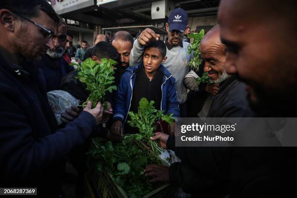 Palestinians are shopping in Nuseirat Market in the central Gaza Strip on March 11 during the first day of Ramadan, amid ongoing battles between...