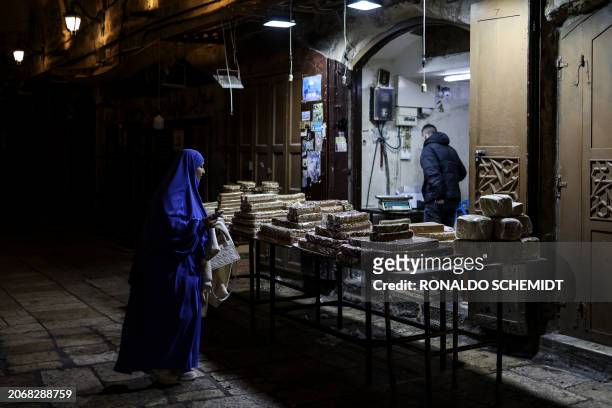 Palestinian woman walks next to traditional sweets inside the Old City in Jerusalem during the Muslim holy fasting month of Ramadan, on March 11 amid...