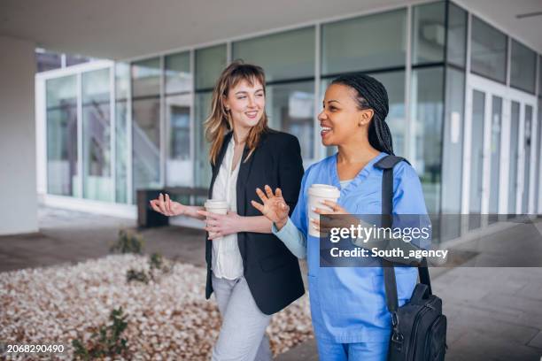 nurse coming to new work and recruiter is welcoming her in front of the hospital - recruiter stockfoto's en -beelden