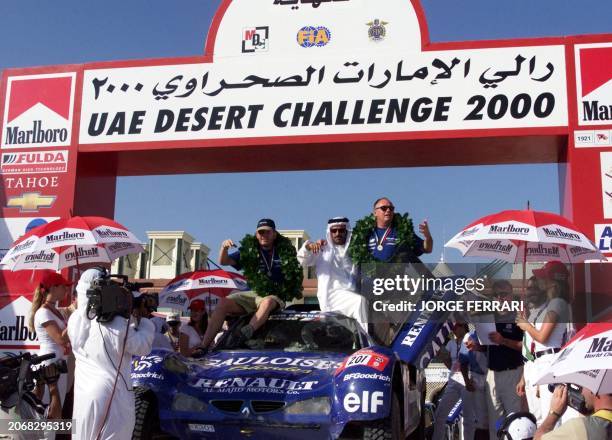 The winner of the UAE Desert Challenge Jean-Louis Schlesser celebrates with co-driver Jean-Marie Lurquin and organizer Mohammed Ben Sulayem on the...