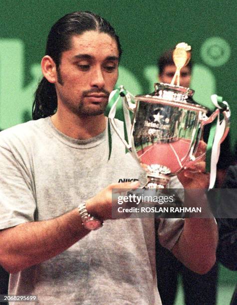 Top seed Marcelo Rios of Chile looks at his winning trophy after defeating Swedish qualifier Mikael Tillstrom 6-4, 7-6 in the final of the 725,000...