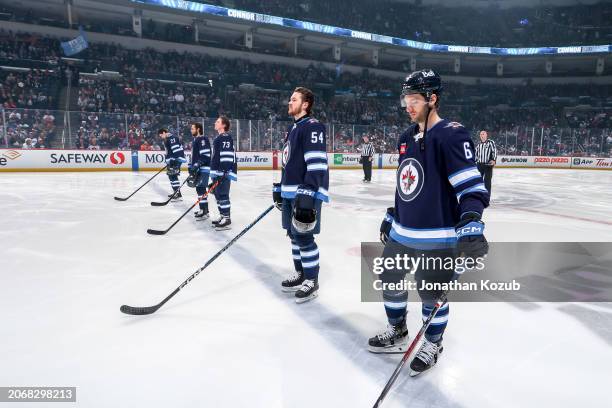 Sean Monahan, Alex Iafallo, Tyler Toffoli, Dylan Samberg and Colin Miller of the Winnipeg Jets stand on the ice prior to puck drop against the...