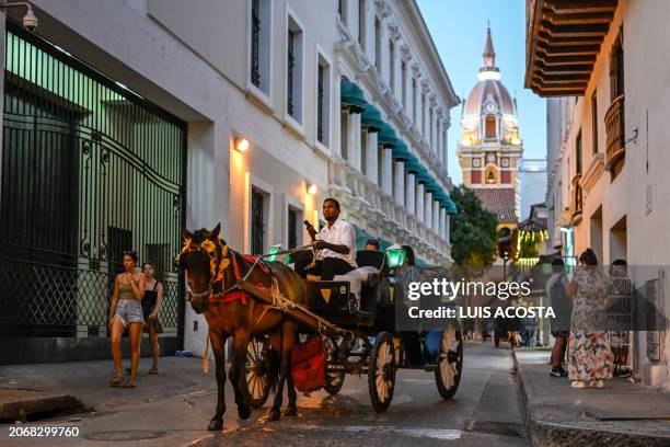 Tourists ride a horse-drawn cart in Cartagena, Colombia, on February 23, 2024. Every year the sea level rises and swallows the bay of Cartagena in...