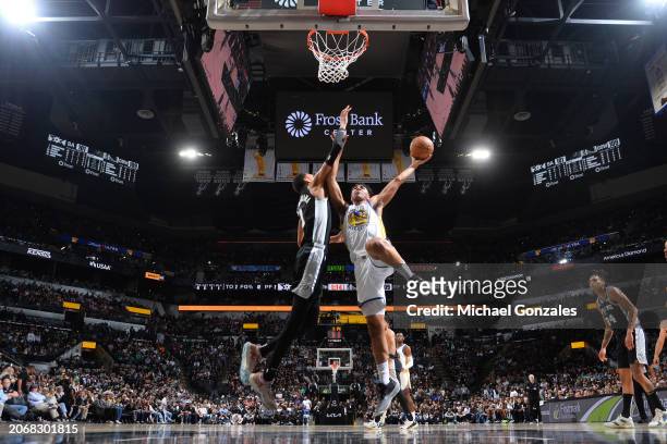 Trayce Jackson-Davis of the Golden State Warriors drives to the basket during the game as Victor Wembanyama of the San Antonio Spurs plays defense on...
