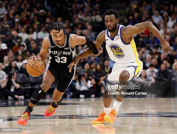 Tre Jones of the San Antonio Spurs drives on Andrew Wiggins of the Golden State Warriors in the first half at Frost Bank Center on March 11, 2024 in...