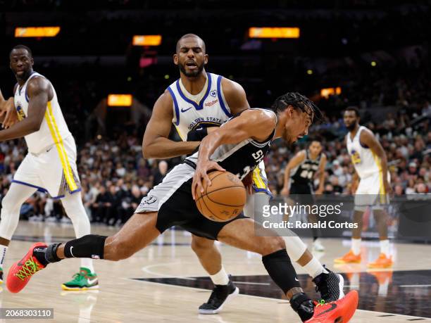 Tre Jones of the San Antonio Spurs drives on Chris Paul of the Golden State Warriors in the first half at Frost Bank Center on March 11, 2024 in San...