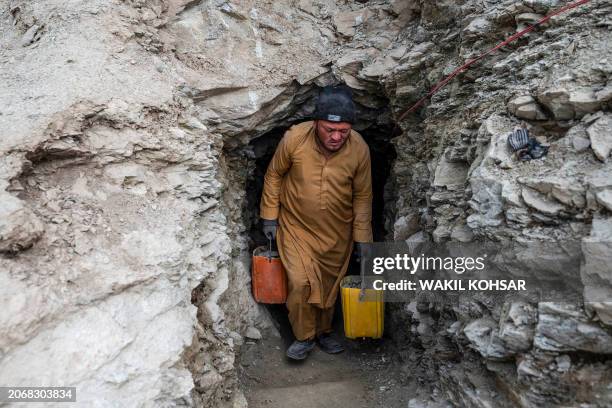 In this photograph taken on February 24 an Afghan man carries containers filled with stones and soil from a tunnel at a gold mine in the mountains of...