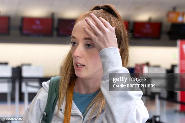 Passenger Ellie Addison gestures as she stands in front of a line of people at the LATAM Airlines check-in counters at Auckland International Airport...